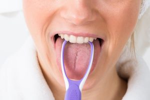 Close-up Of A Woman Cleaning Her Tongue