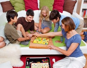 a young family is playing board-games in their bed