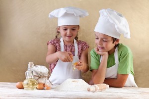Kids with chef hats preparing the cake dough - mixing ingredient