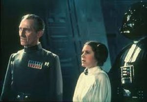 (left-right) Peter Cushing, Carrie Fisher, and Dave Prowse in the Darth Vader suit, in Star Wars Episode IV. (Image sourced via google images)