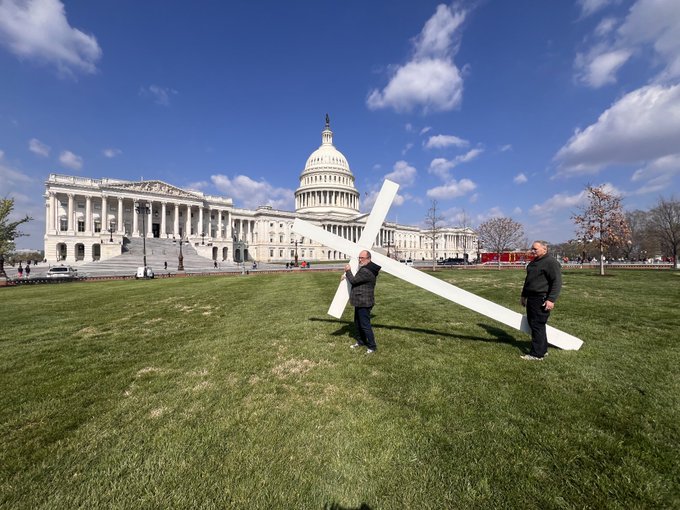 Two men carrying large white cross to the U.S. Capitol steps
