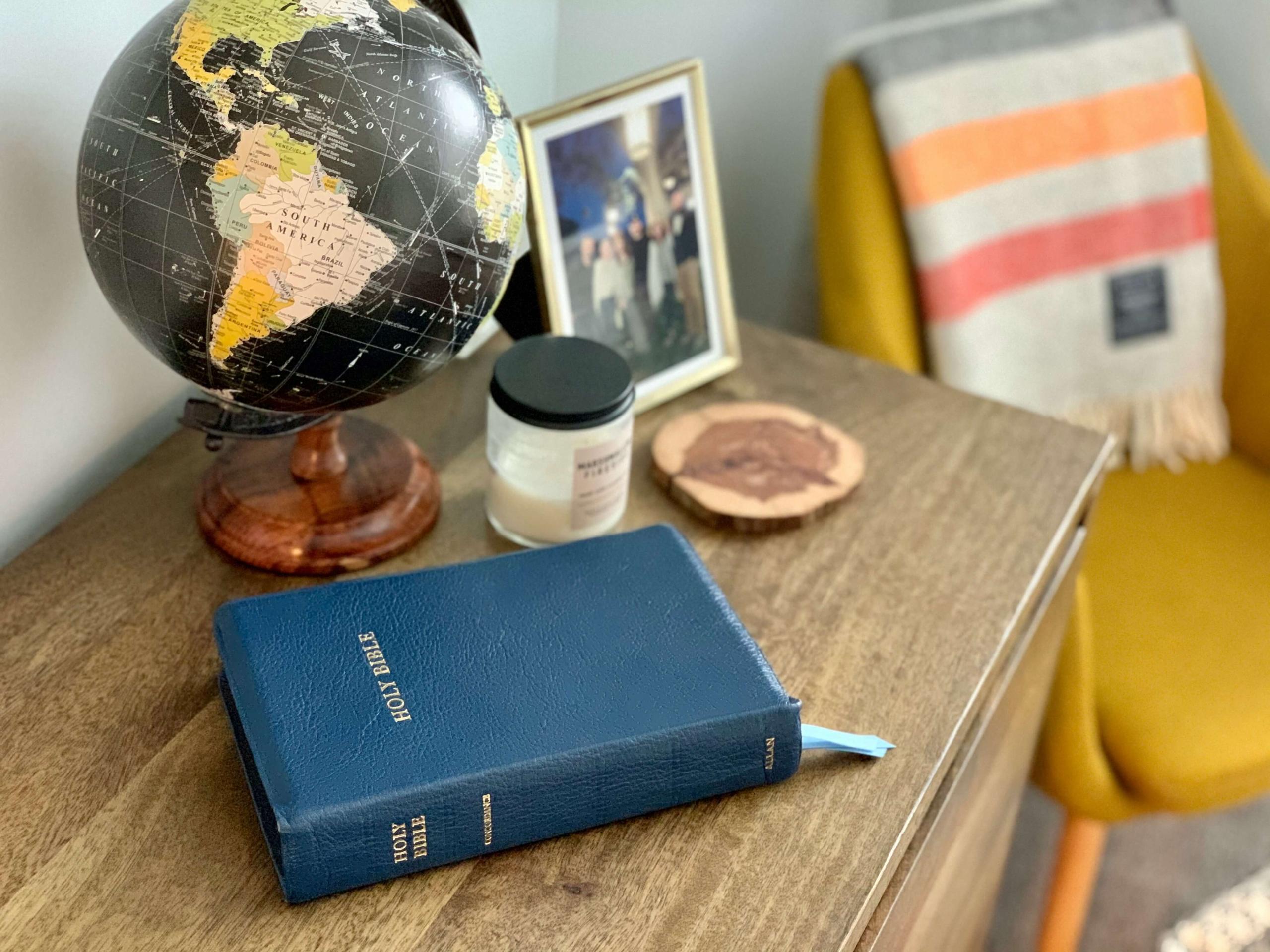 The Bible on a desk with a globe
