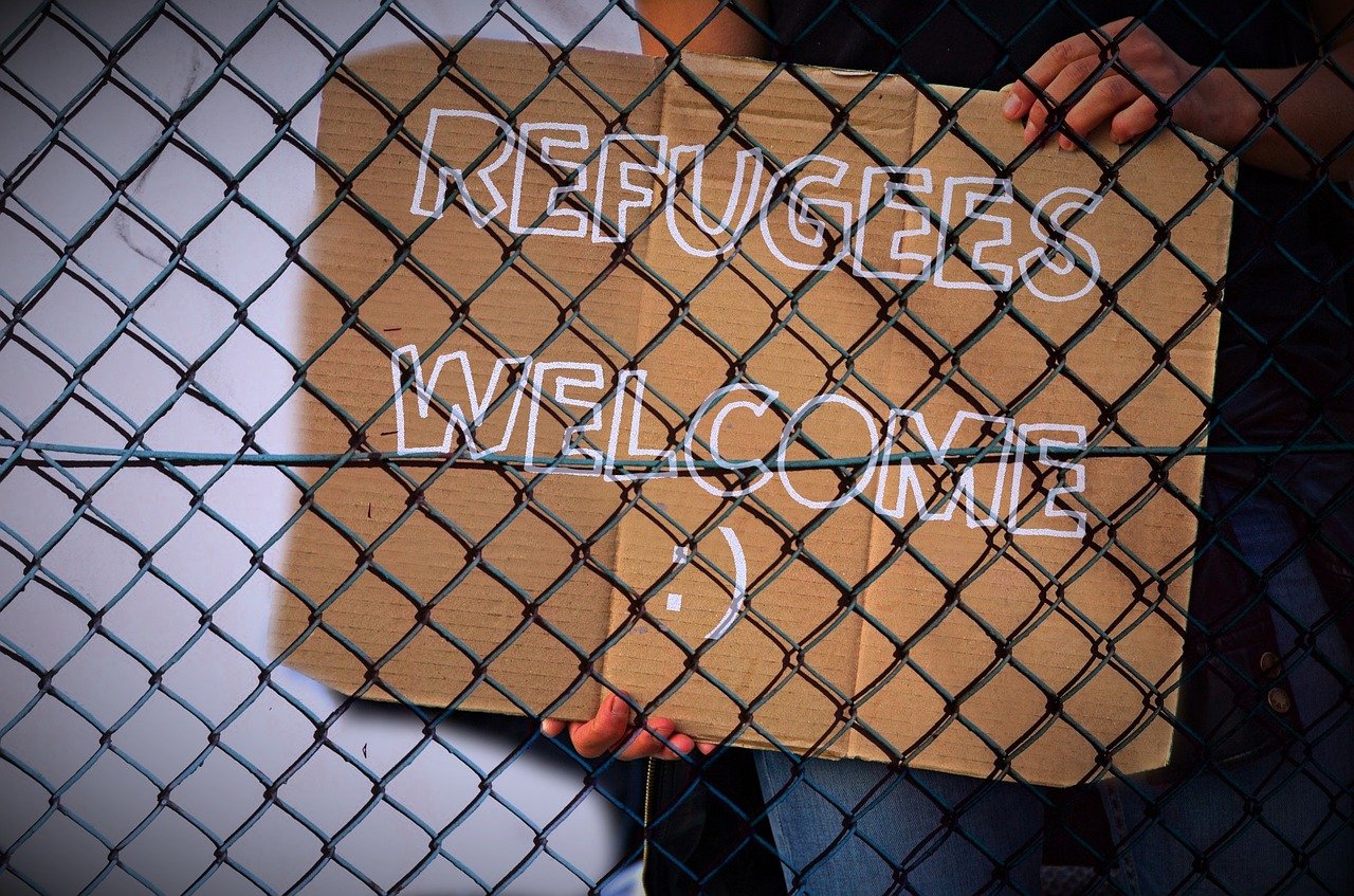 "Refugees Welcome" sign behind chain-mail fence