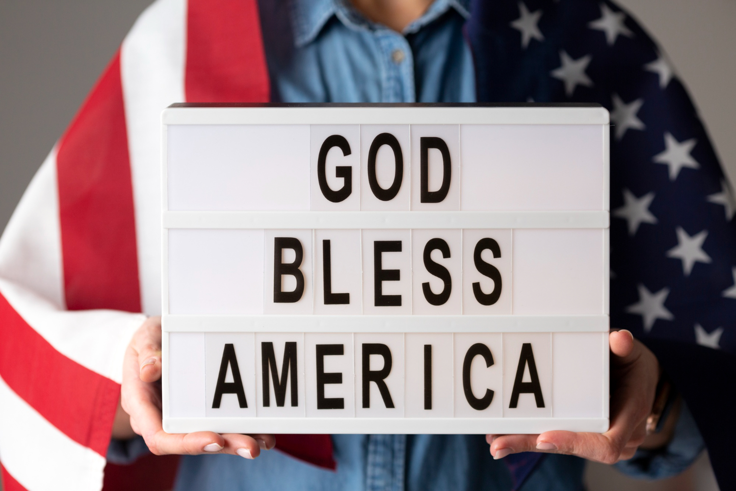 Man wrapped in American flag holding "God Bless America" sign