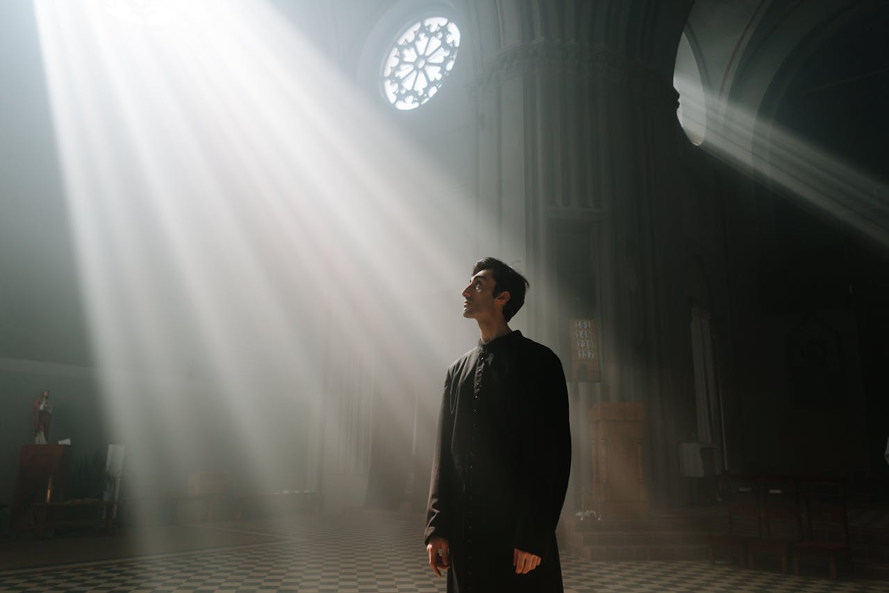 Man standing alone in a cathedral under a ray of sunlight through a ceiling window