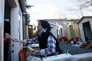 Volunteer B.T. Eberhart hands off a level during the final stages of construction on the Central District's new tiny house village on Friday, Jan. 22, 2016. (GRANT HINDSLEY, seattlepi.com)